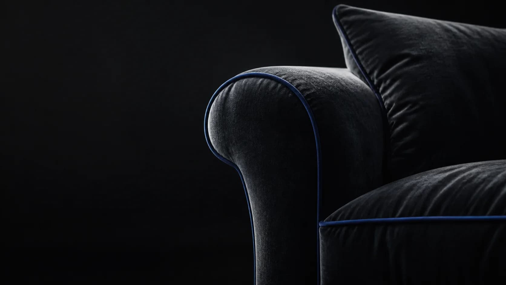 Détail d’un canapé en velours anthracite bordé de bleu
