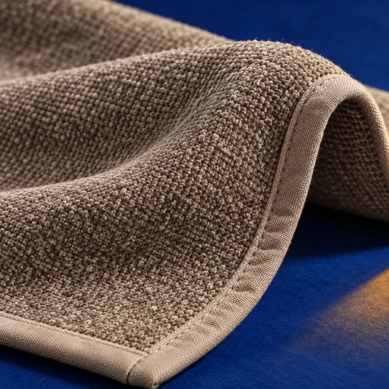 Gros plan sur le tissage chenille taupe et sa bordure cousue